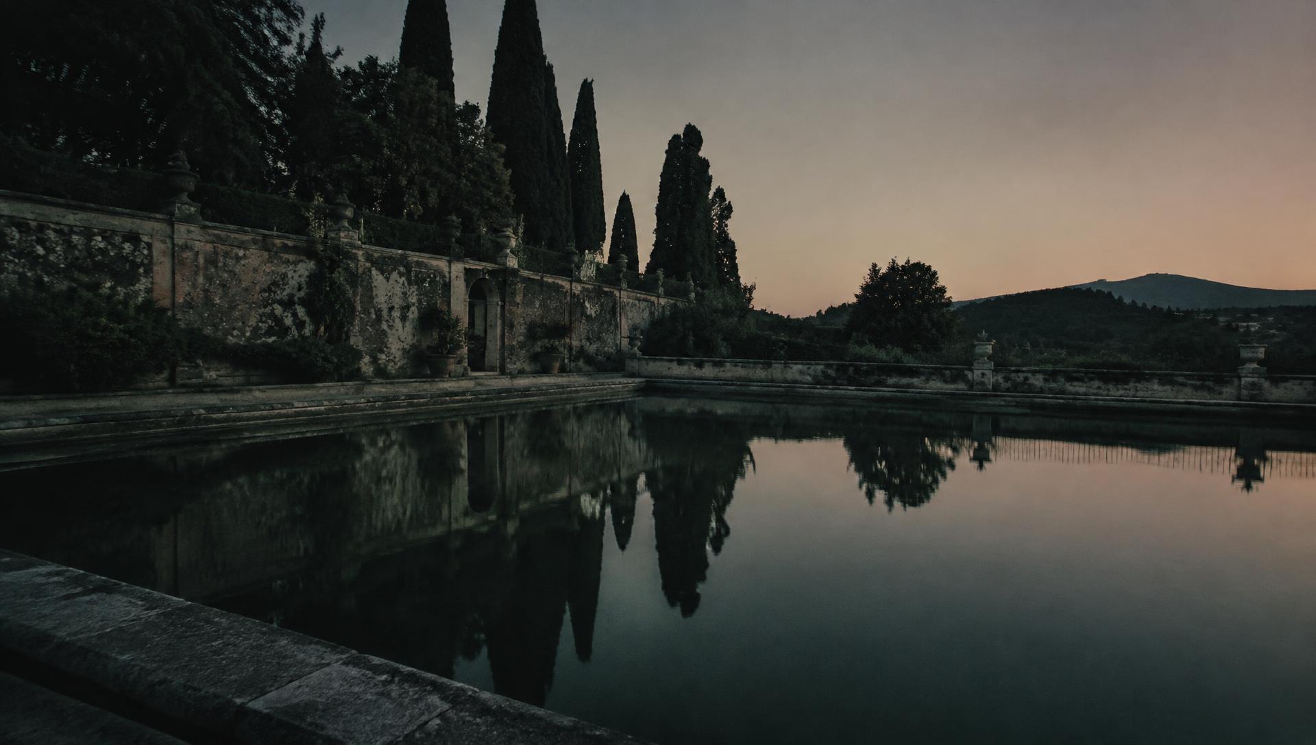 Still water of a stone garden pool at dusk