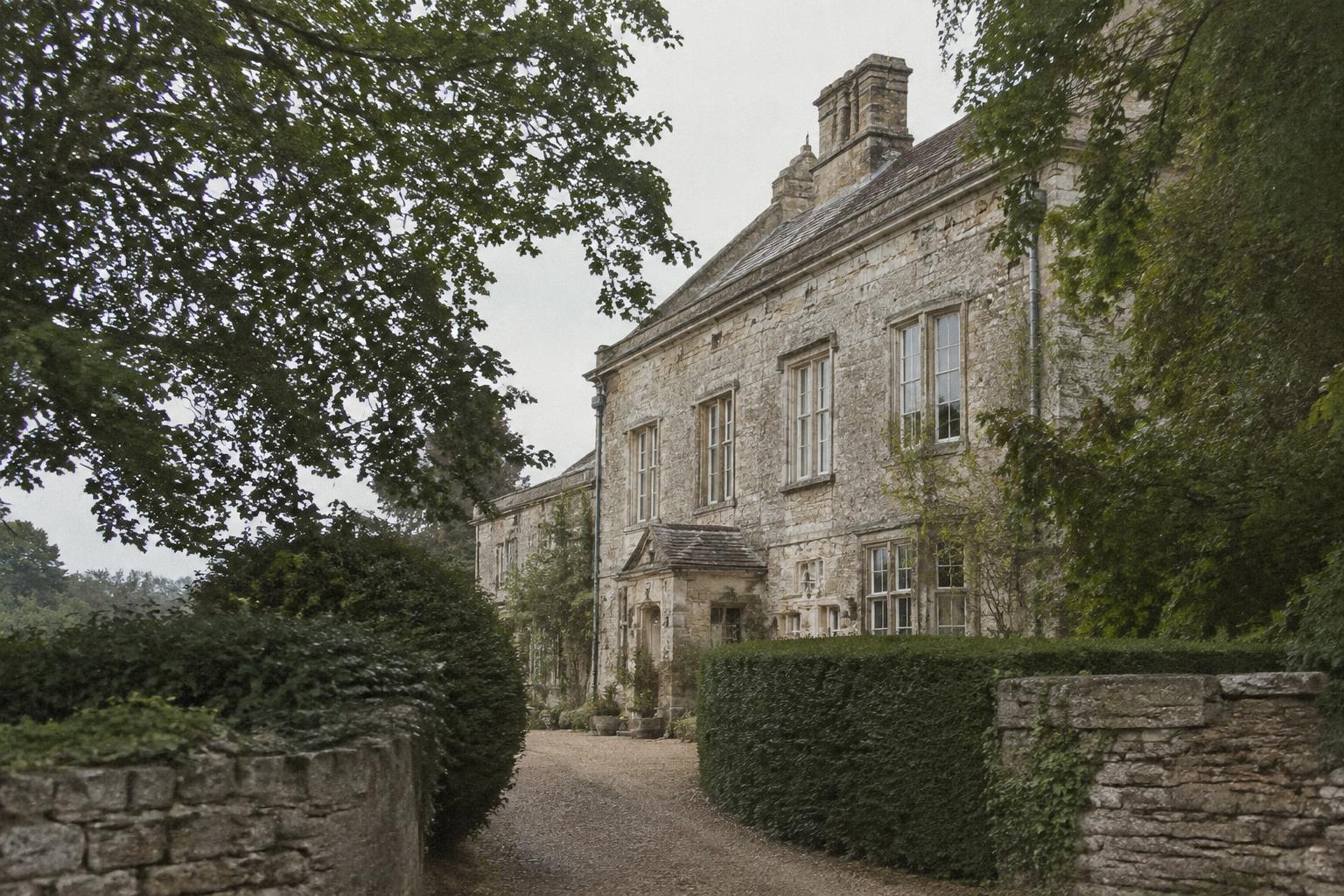Limestone facade of a historic country estate behind mature hedges